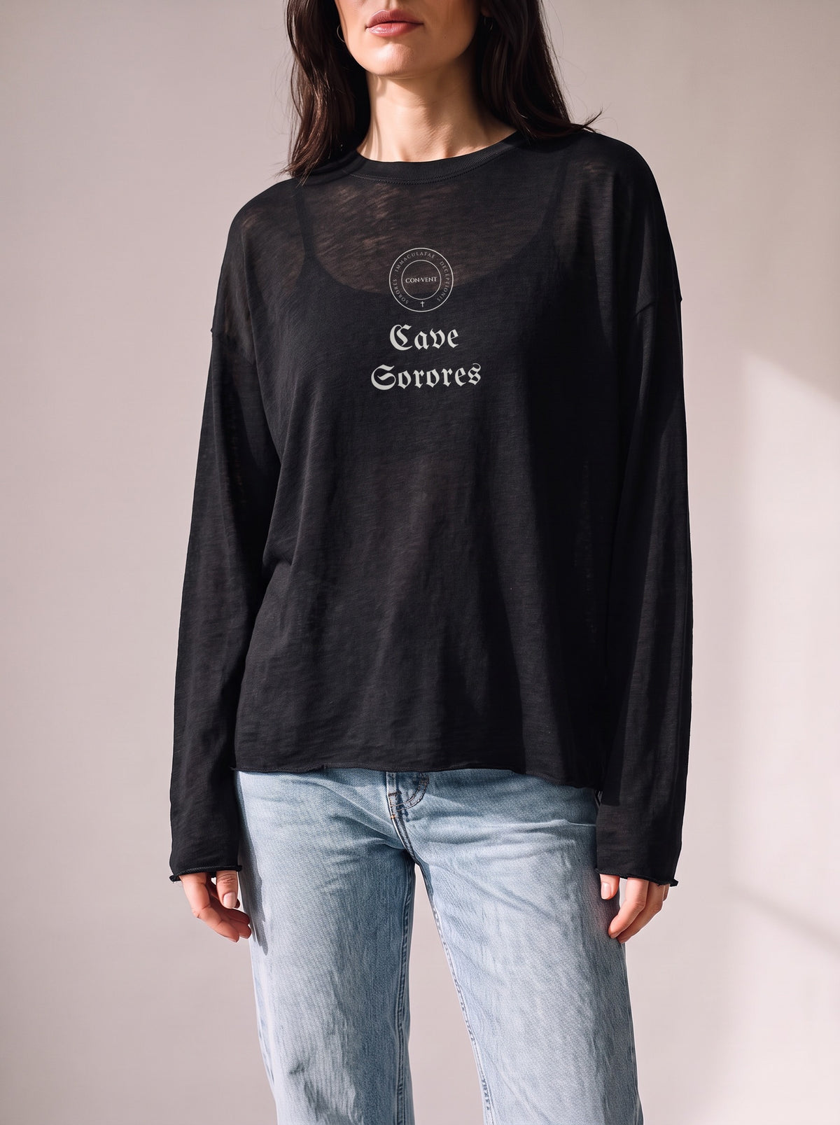 Worn by a woman: Her Sheer Long Sleeve, Cave Sorores on a black sheer raw-edge long sleeve over a black camisole