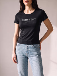 Worn by a woman: Her Baby Tee (Tencel), CON·VENT on a black fitted Tencel baby tee with light blue jeans