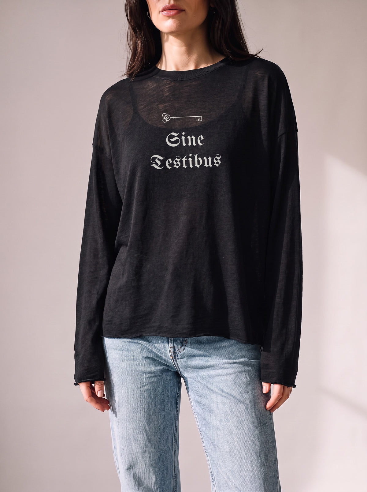 Worn by a woman: Her Sheer Long Sleeve, Sine Testibus on a black sheer raw-edge long sleeve over a black camisole