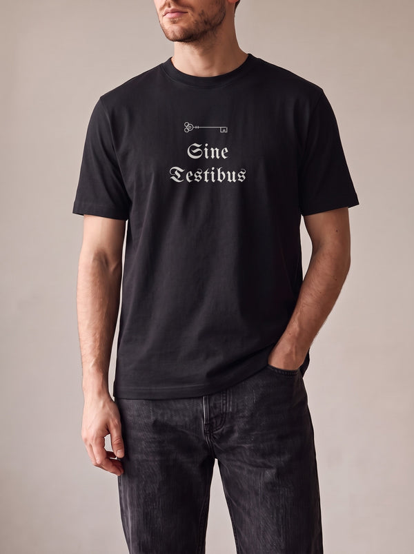 Worn by a man: His Tee, Sine Testibus on a black regular-fit tee with black jeans