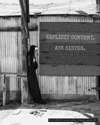 Sister Antonia beside a barn wall covered by a board reading EXPLICIT CONTENT. ASK SISTER., black and white photograph with the board added for the website