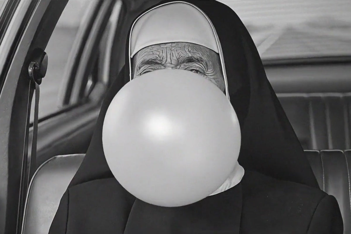 Sister Antonia blowing a bubblegum bubble in her car