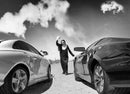 Sister Antonia between two cars on a desert road, black and white photograph, Salton Sea, 1 May 2016